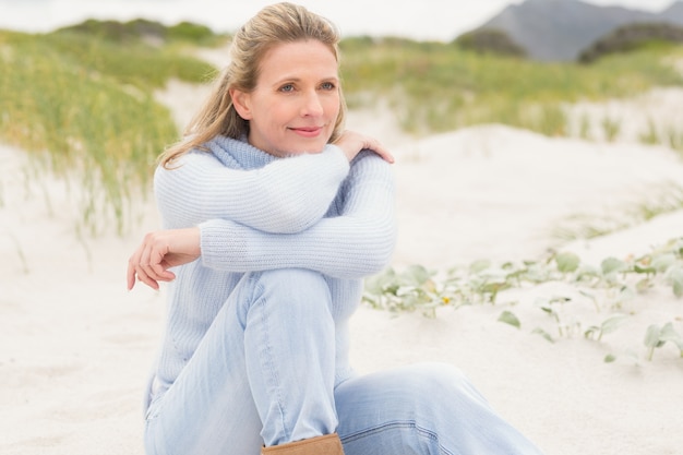 Femme souriante assise sur le sable