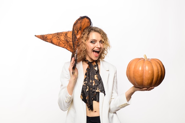 Femme souriante au chapeau de sorcière avec citrouille. Joyeux Halloween. Préparation des vacances d'Halloween. Femme sorcière à la citrouille. Fête d'Halloween. Femme émotive en costume d'halloween de sorcière avec jack o lantern.