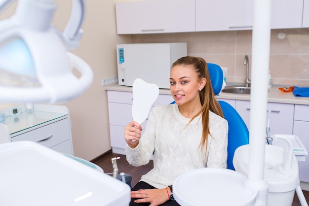 Femme souriante au dentiste assis dans une chaise de dentiste prêt pour un examen dentaire.