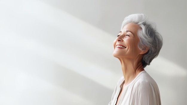 Une femme souriante aux cheveux gris regarde vers le haut l'espace vide