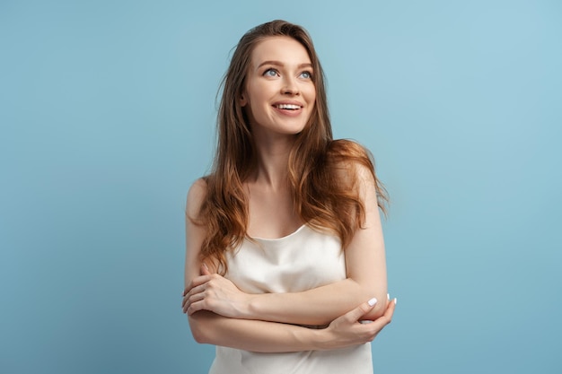 femme souriante aux cheveux longs et en bonne santé souriante en regardant la caméra isolée sur un fond bleu