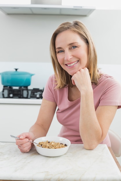 Femme souriante ayant des céréales dans la cuisine