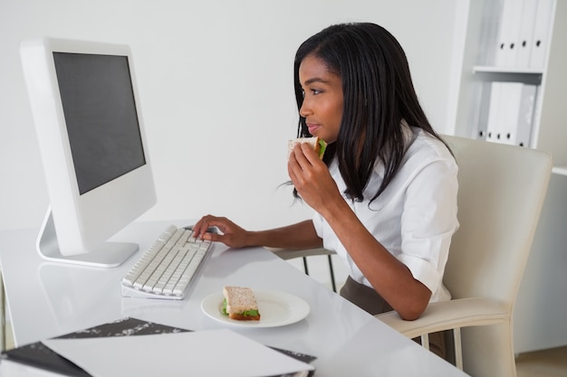 Femme souriante ayant un sandwich à son bureau