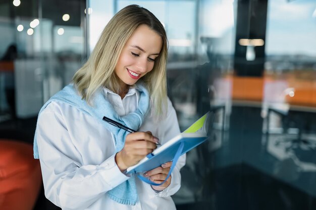 Femme souriante blonde prenant des notes dans un cahier