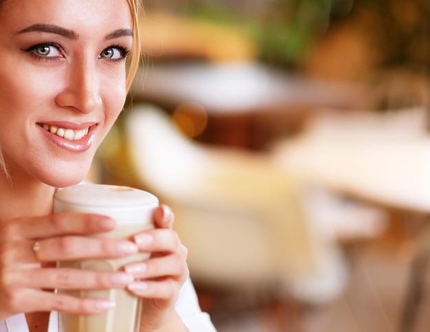 Femme souriante de bonne humeur avec une tasse de café assis dans un café