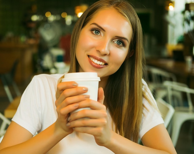 Femme souriante de bonne humeur avec une tasse de café assis dans un café