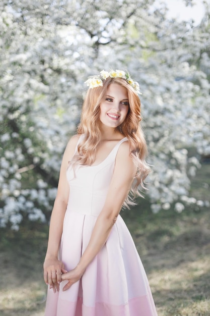 Femme souriante avec une branche d'arbre en fleurs au parc du printemps