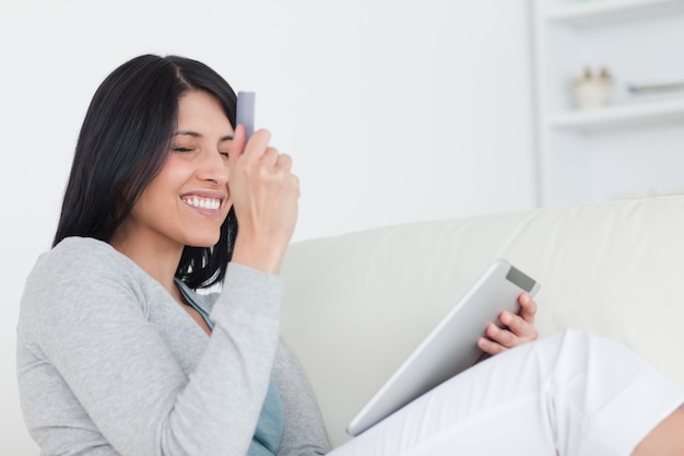 Femme souriante brandissant une carte de crédit et une tablette