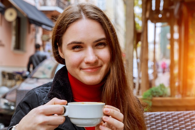 Femme souriante, buvant du café au café de rue