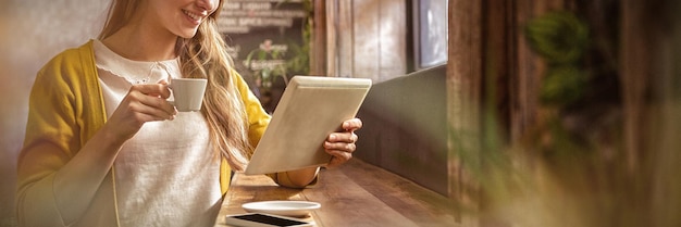 Femme souriante buvant du café et utilisant une tablette