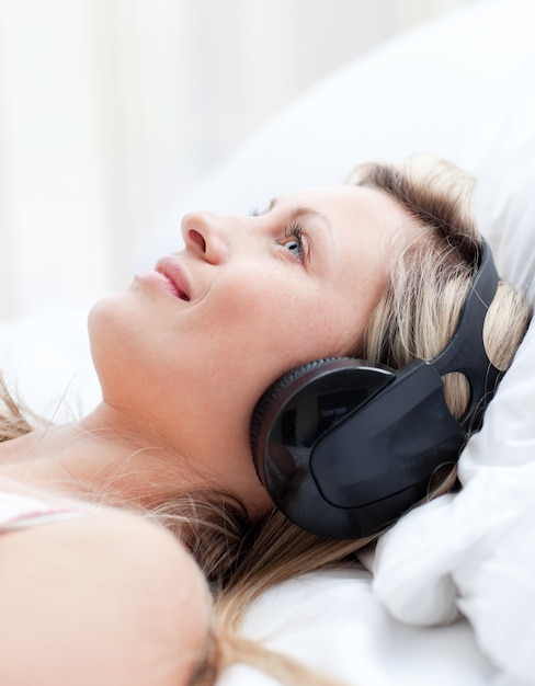 Femme souriante avec un casque sur un lit