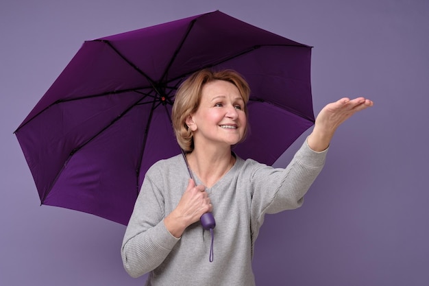 Femme souriante caucasienne senior avec parapluie prêt pour la pluie