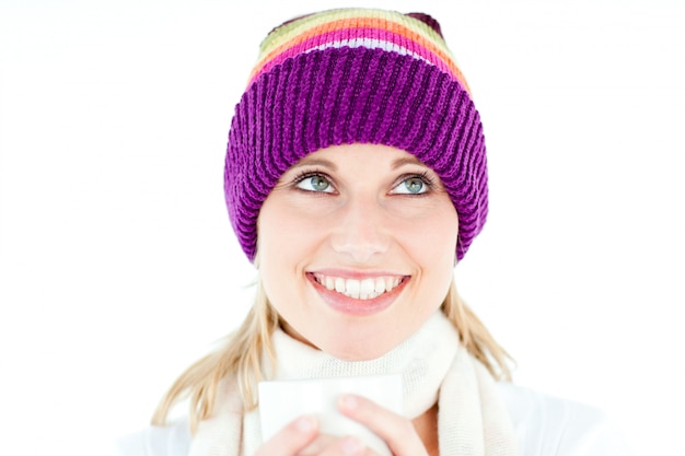 Femme souriante avec un chapeau coloré et une tasse dans ses mains