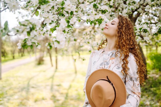 Femme souriante avec chapeau dans le parc du printemps Le concept de liberté de voyage relaxante