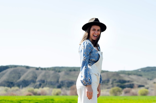 Photo femme souriante avec chapeau par une journée ensoleillée