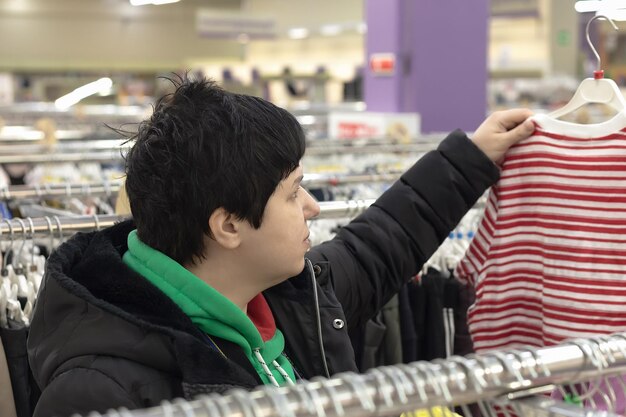 Une femme souriante choisit des vêtements décontractés dans un magasin Commerce de détail