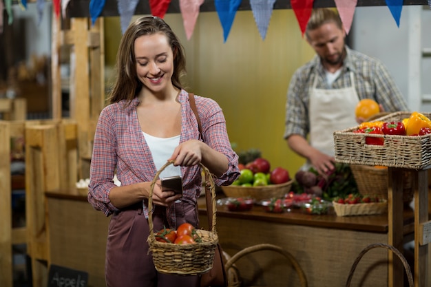 Femme souriante en cliquant sur l'image de tomates dans le panier