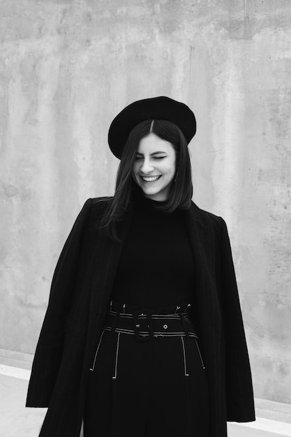 Une femme souriante contre le mur.