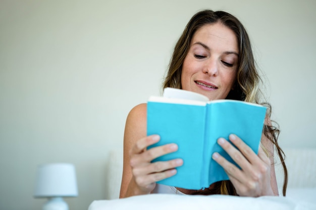 femme souriante, coucher, lecture, livre, lit