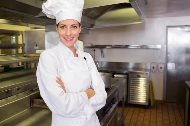 Femme souriante cuisinier avec les bras croisés dans la cuisine