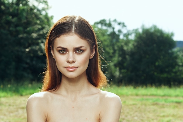 Femme souriante dans un champ à l'extérieur des épaules nues modèle de peau claire