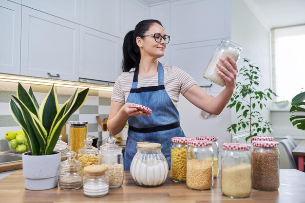 Femme souriante dans la cuisine avec des bocaux de nourriture stockée