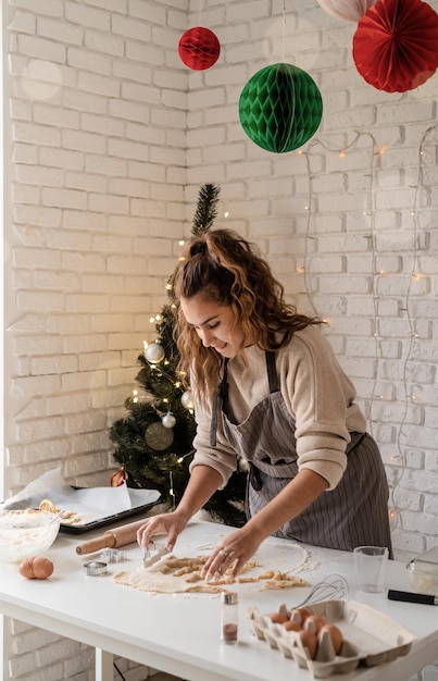 Femme souriante dans la cuisine préparant des biscuits de Noël