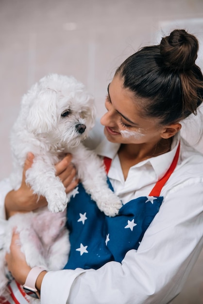 Femme souriante dans la cuisine tenant un mignon chien maltais blanc