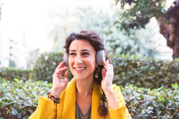 Femme souriante dans un parc avec un casque sur la tête