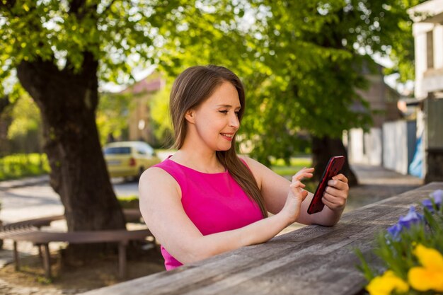 Femme souriante dans la rue utilisant un téléphone portable et ayant un appel vidéo