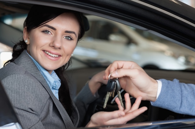 Femme souriante dans une voiture recevant des clés de voiture