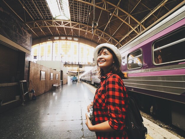 Photo une femme souriante debout à côté du train sur la plate-forme de la gare