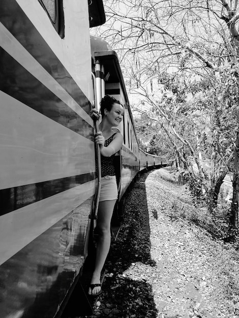 Une femme souriante debout sur la porte du train