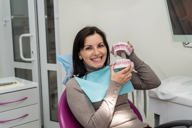 Femme souriante en dentisterie avec modèle de mâchoire