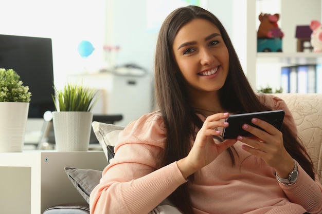 Femme souriante détendue sur un canapé à la maison à l'aide d'un smartphone et de textos