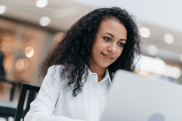 Une femme souriante dirige son blog dans la cafétéria d'un centre commercial