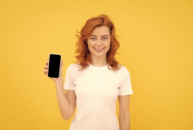 Femme souriante discutant dans un smartphone ou faisant des achats en ligne sur la communication de fond jaune