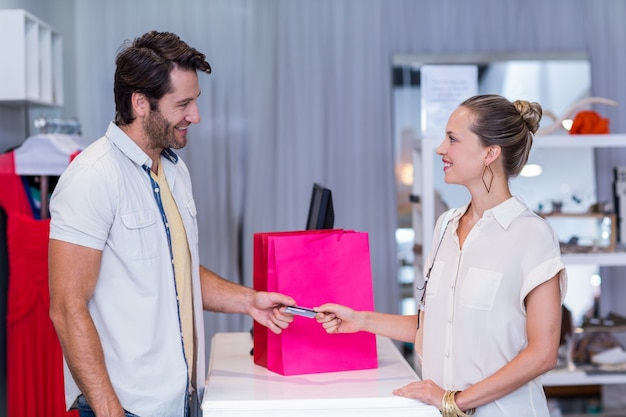 Femme souriante donnant une carte de crédit à la caissière