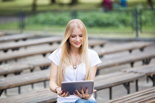 Femme souriante du millénaire debout à l'aide d'un gadget de tablette moderne à la maison naviguant sur Internet ou faisant du shopping heureuse satisfaite jeune cliente surfant sur le web lire des nouvelles ou discuter sur le concept de technologie de tablette