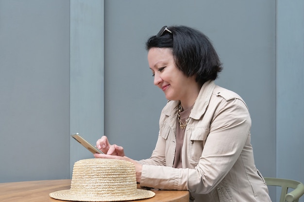 Photo une femme souriante est assise à une table dans un café et écrit des messages au téléphone.