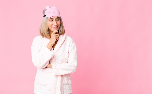 Photo femme souriante avec une expression heureuse et confiante avec la main sur le menton, se demandant et regardant sur le côté