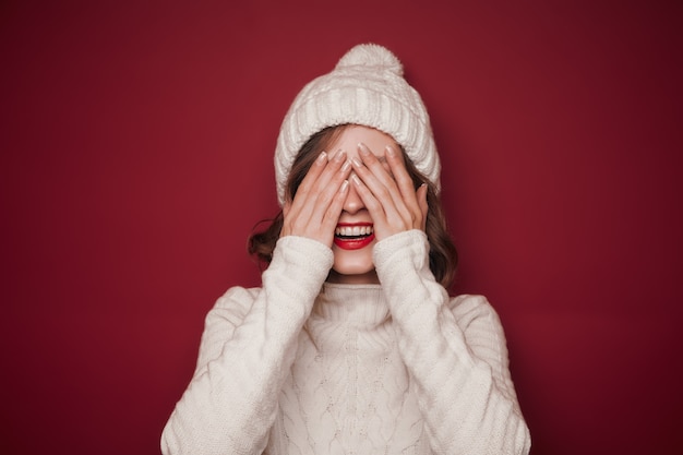 Une femme souriante gaie en pull couvre ses yeux