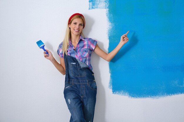 femme souriante heureuse peignant un mur blanc intérieur de couleur bleue et verte de la nouvelle maison