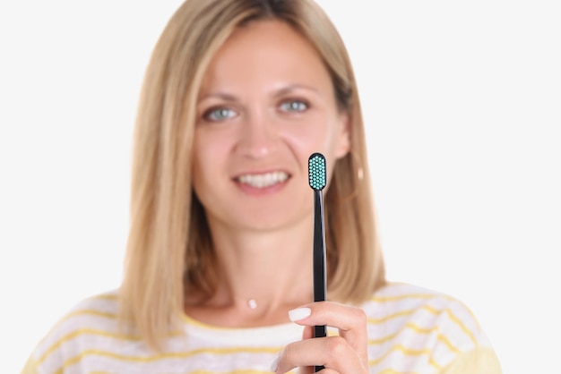 Une femme souriante heureuse prend soin des dents et montre une brosse à dents