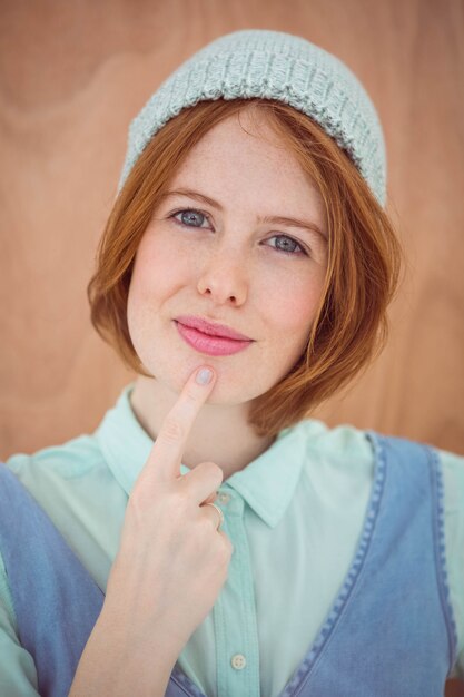 femme souriante de hipster coiffé d'un chapeau bonnet avec sa main à son visage