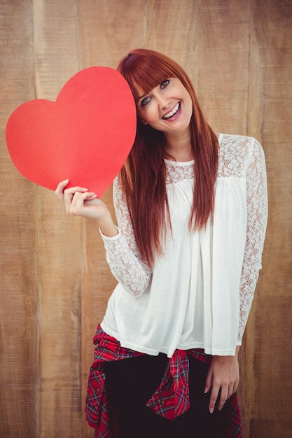 Femme souriante de hipster avec un grand coeur rouge