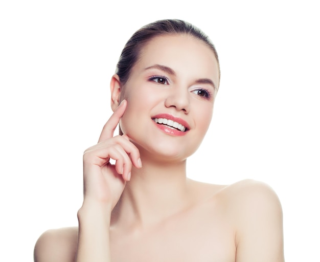 Femme souriante isolée sur fond blanc Belle jeune modèle de spa avec une peau saine touchant son visage sa main Traitement du visage cosmétologie beauté soins de la peau et spa