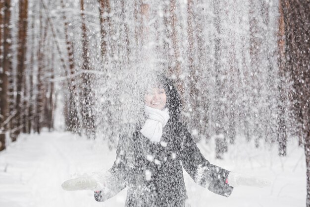 Photo une femme souriante jetant de la neige en plein air pendant l'hiver