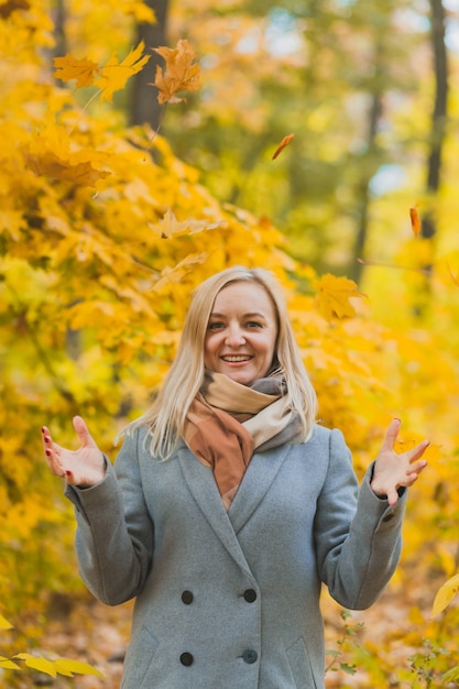 Une femme souriante a jeté un tas de feuilles.