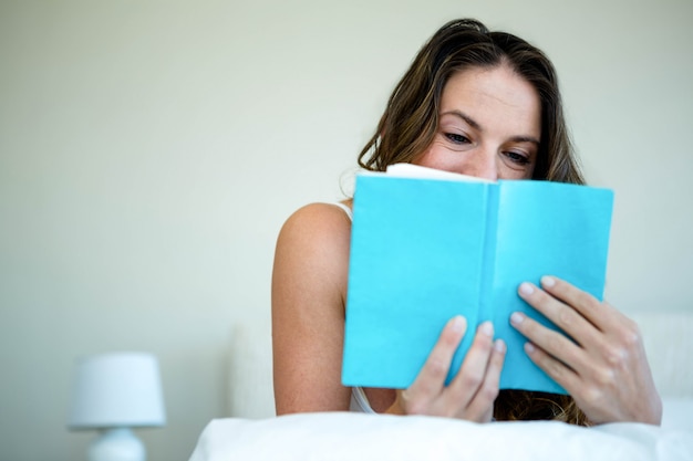 femme souriante, lecture, livre, lit